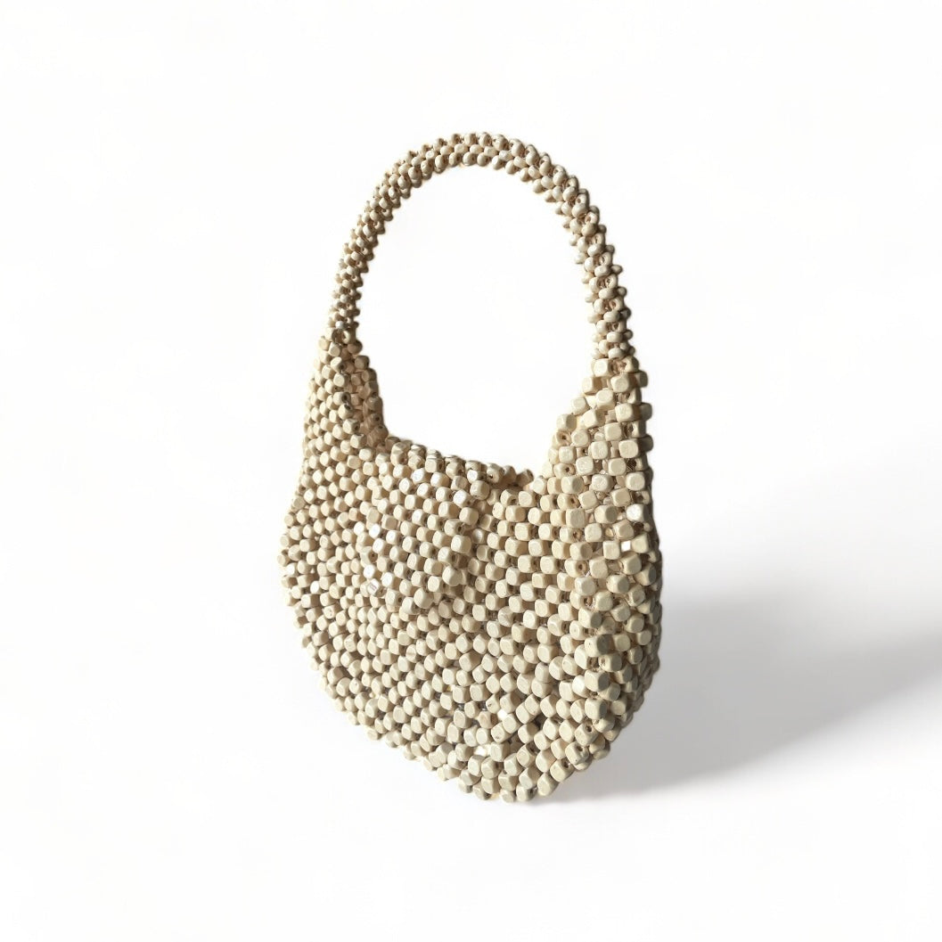 The Carmela handmade statement bag in Natural color, made from wooden beads.